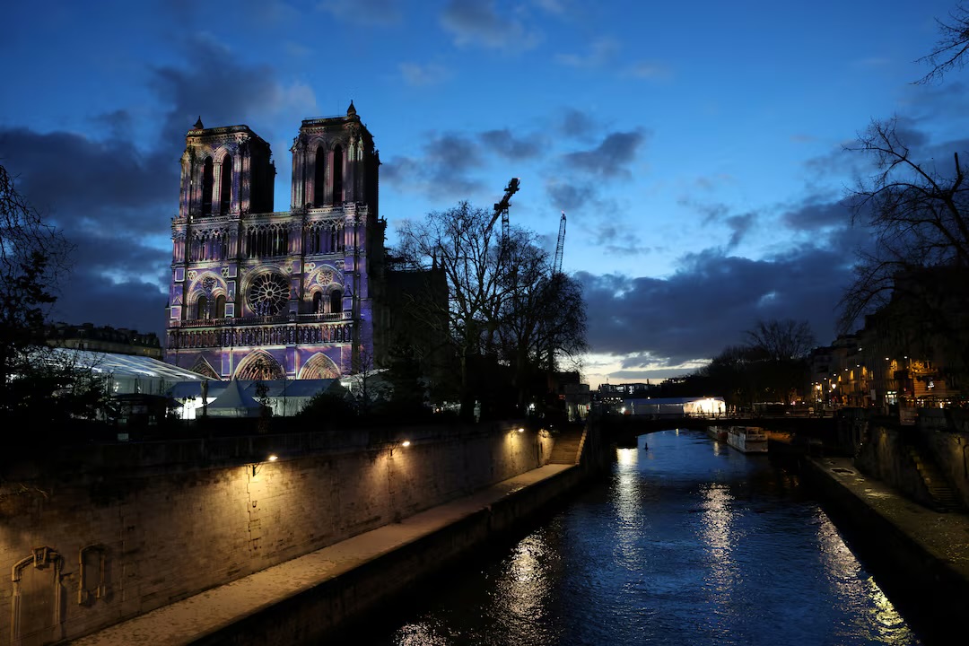 Notre-Dame i Paris oplyst ved Seinens bred ved mørkets frembrud